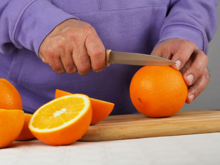 man cuts oranges