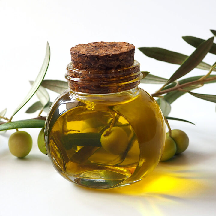 Оливковое масло на фоне веток оливы